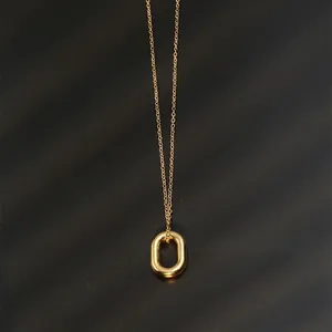 Flat lay of minimalist gold oval pendant necklace on a textured black background