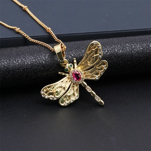 Macro shot of dragonfly pendant with gold plating, red center stone and zircon details