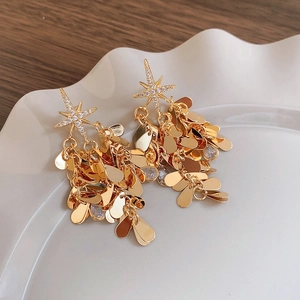Détail de boucles d'oreilles étoile dorées avec zircon et pampilles gouttes d'eau