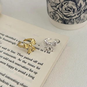 Detailed view of gold and silver bow rings with adjustable bands on a vintage book