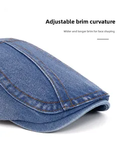 Close-up of washed blue denim beret showing yellow stitching and adjustable curved brim