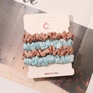 Set of four satin scrunchies in pink and blue colors on a white display card