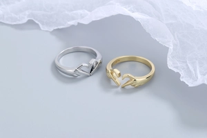 Macro shot of gold and silver S925 sterling silver rings featuring a heart gesture design