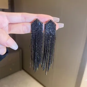 Close-up of elegant black tassel earrings with geometric crystal accents and fine metal chains