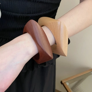 Vue détaillée de larges bracelets en bois minimalistes avec grain naturel sur un poignet féminin