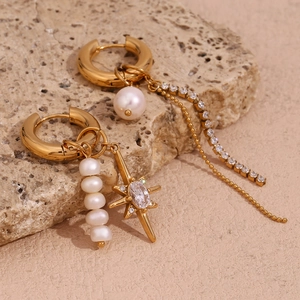 Macro shot of asymmetric gold star earrings with freshwater pearls and zircon tassels