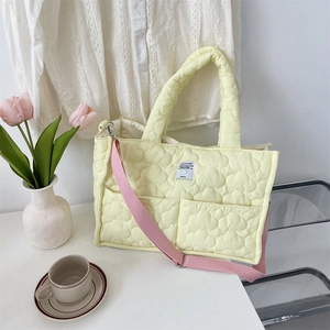 Dettaglio della trama trapuntata su borsa gialla con tasche e tracolla rosa regolabile
