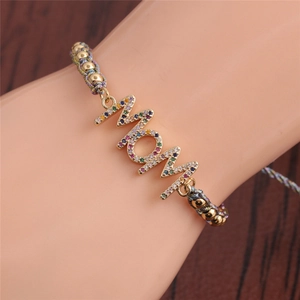 Detailed shot of gold MOM charm bracelet with colorful pavé crystals on a woven cord band