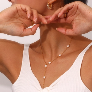 Detail of elegant gold Y-shaped pearl necklace set with matching earrings and ring