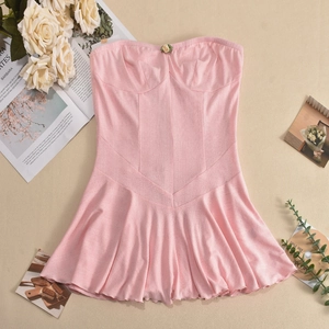 Detailed view of pink tube dress with floral embroidery and ruched hem on a textured surface