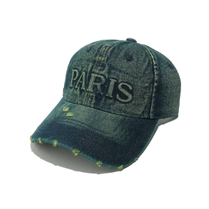Close-up of PARIS embroidery and distressed edge details on washed denim baseball cap