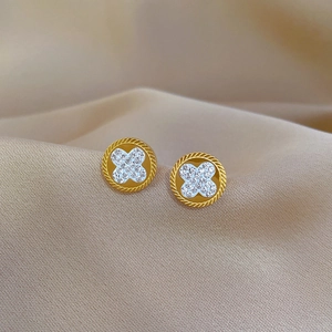 Minimalist four-leaf clover stud earrings with sparkling crystals on champagne silk