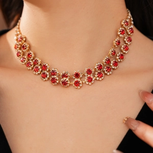Detail of a double-layered gold necklace with red gemstones and crystals on a model