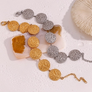 Dettaglio di bracciali a disco rotondo martellato in oro e argento su sfondo bianco