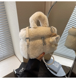 Close-up of white plush crossbody bag with straw hat charm and handle in a vanity setting