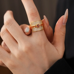 Detailed macro view of wide gold band ring with emerald-cut red gemstones and micro-pave diamonds