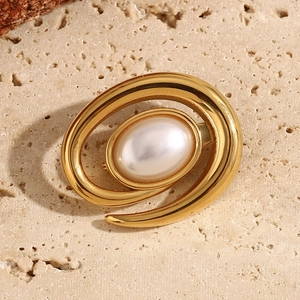 Macro detail of 18K gold plated spiral conch brooch with a white center pearl inlay