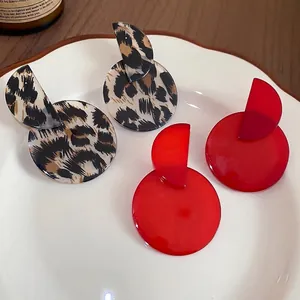 Retro geometric leopard print and red resin drop earrings on a white ceramic tray