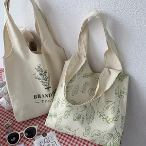 Detail of canvas tote bags featuring green plant prints and sturdy texture on a plaid cloth