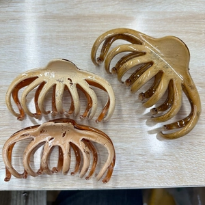 Detailed view of three large amber tortoiseshell hair claws on a light wood surface
