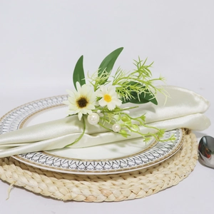 Portatovagliolo con margherita, foglie verdi e perle su tovagliolo di raso verde