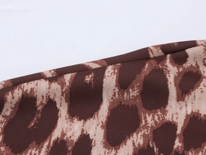Detailed macro view of classic leopard print fabric with precise hemmed edge stitching
