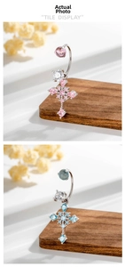 Details von rosa und blauen Hufeisen-Bauchnabelpiercings mit Kristallkreuzen auf Holz