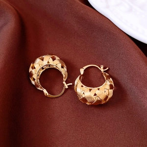 Close-up of 18k gold plated U-shaped hoop earrings with woven texture on silk