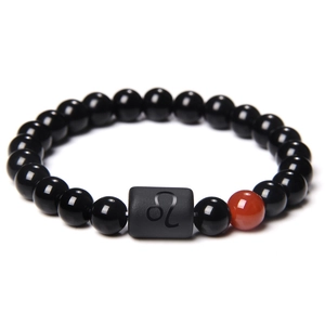 Macro view of black and red stone bead bracelet featuring the Leo zodiac symbol bead
