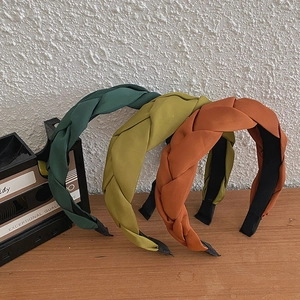 Detail of hand-woven braided wide headbands in vintage green, mustard yellow, and orange