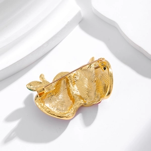 Back view of gold-tone creative apple brooch featuring a safety pin and brushed metal finish