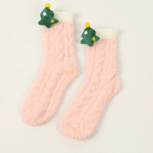 Detail von flauschigen rosa Korallenfleece-Socken mit 3D Weihnachtsbaum-Puppe Dekor