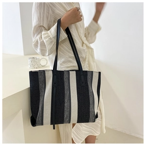 Close-up of a striped tote bag with elegant black and white vertical patterns on canvas