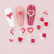Close-up of red heart rhinestones and silver metal alloy nail art decorations on pink base