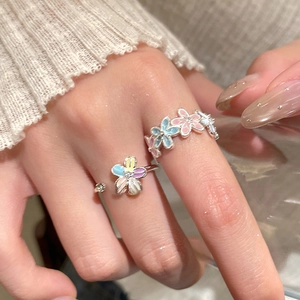 Detailed close-up of macaron-colored flower rings with zircon accents on a model hand