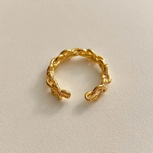 Detail of minimalist gold woven chain style open ring with smooth metallic finish