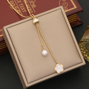 Golden snake chain necklace with pearl and white clover pendant on elegant jewelry box