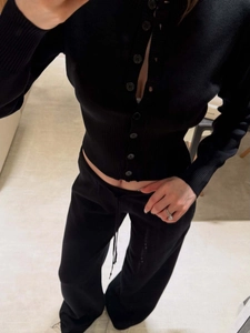 Close-up of black slim-fit knit cardigan with multiple buttons and matching trousers