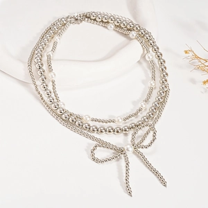 Close-up of three-layered silver beaded necklace with white pearls and a bow pendant