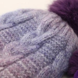 Close-up of thick knit texture and soft purple pompom on children's winter beanie hat