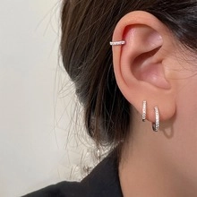 Detail of silver S925 earrings set with white zircon stones worn on the earlobe