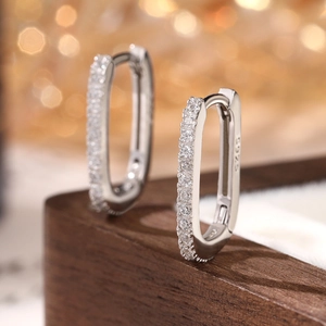 Macro shot of S925 sterling silver hoop earrings with white cubic zirconia on wood