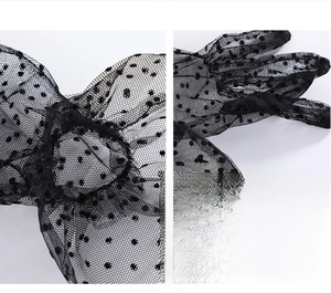 Detailed view of sheer black polka dot lace gloves with delicate ruffled wrist trim