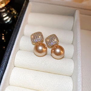 Détail de boucles d'oreilles perles champagne et zircons sur boîte à bijoux blanche