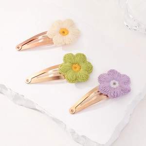 Detail view of three handmade crochet flower hair clips in macaron colors on a tray
