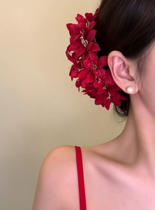 Detail view of an elegant red fabric flower hair pin worn on model hair accessory