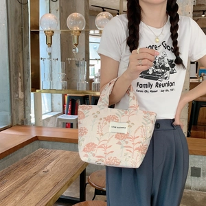 Detailansicht der Canvas-Handtasche mit Blumenmuster und Love Sozakka-Etikett im Café