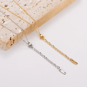 Close-up of gold and silver V-shaped necklaces with 18KGP hallmark on beige stone