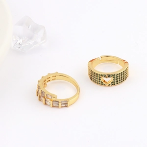 Detail of adjustable gold rings with square white zircon and green heart accents