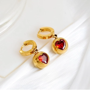Vue détaillée de boucles d'oreilles boules dorées avec zircon coeur rouge